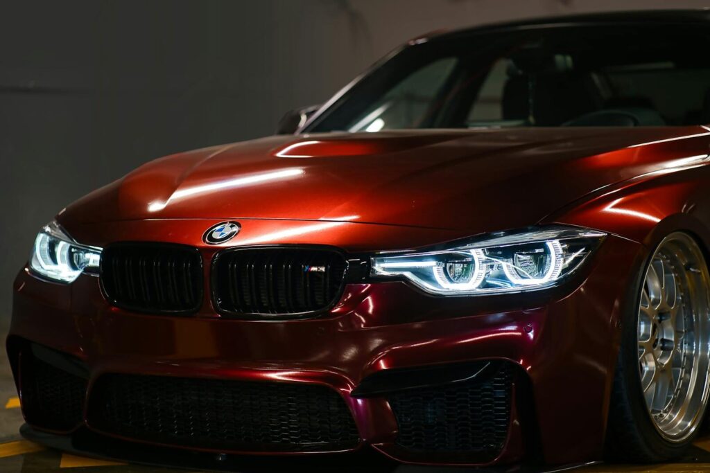 Close-up of a luxury red BMW with a sleek, shiny hood captured indoors.